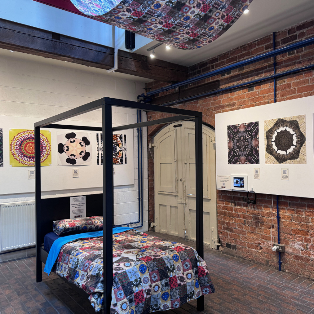 installation view of exhibition consisting of four poster bed and patterns on quilt and overhanging shade